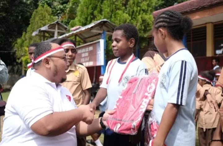 General Manager Consumer Business Telkomsel Region Maluku Papua Fajri Adi Firmansyah pada saat memberikan bantuan pada seorang siswa di Sentani, Papua.